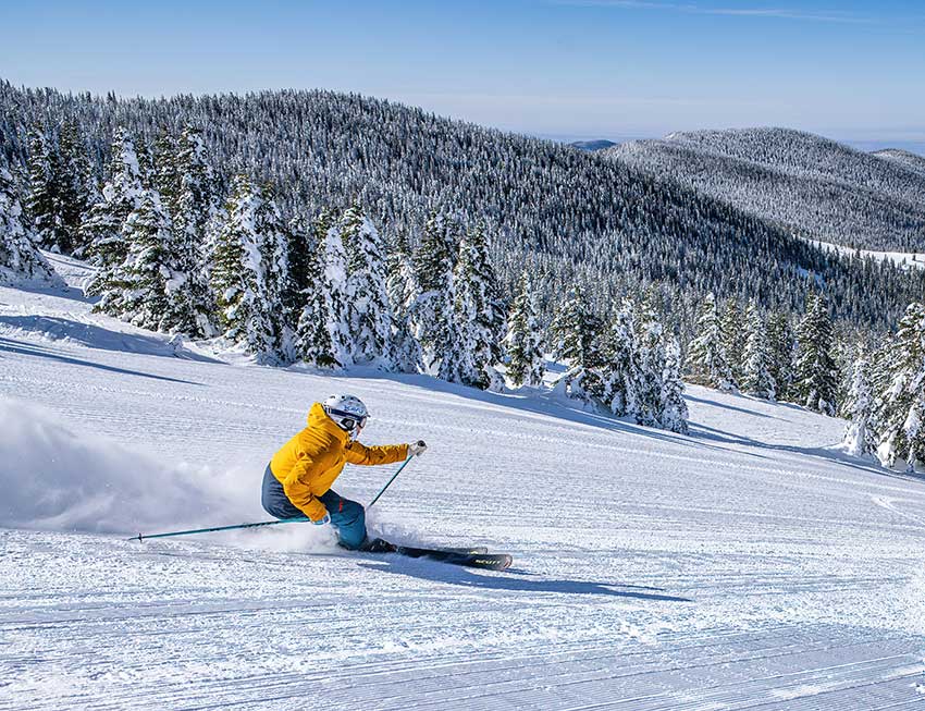 A skier enjoys some fast, big soft turns on Gayway at Ski Santa Fe on a typical sunny day. Photo credit: Mountain Standard Creative.